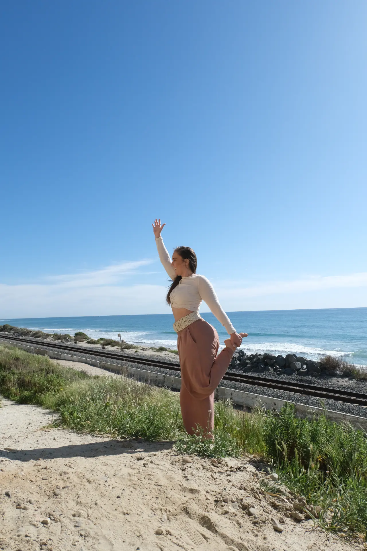 Katsina Bhatia in a yoga pose on a coastal path beside railroad tracks