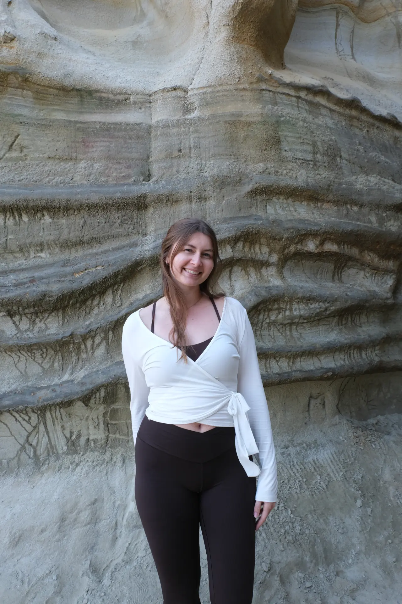 Hannah Milner smiling in front of a textured rock wall