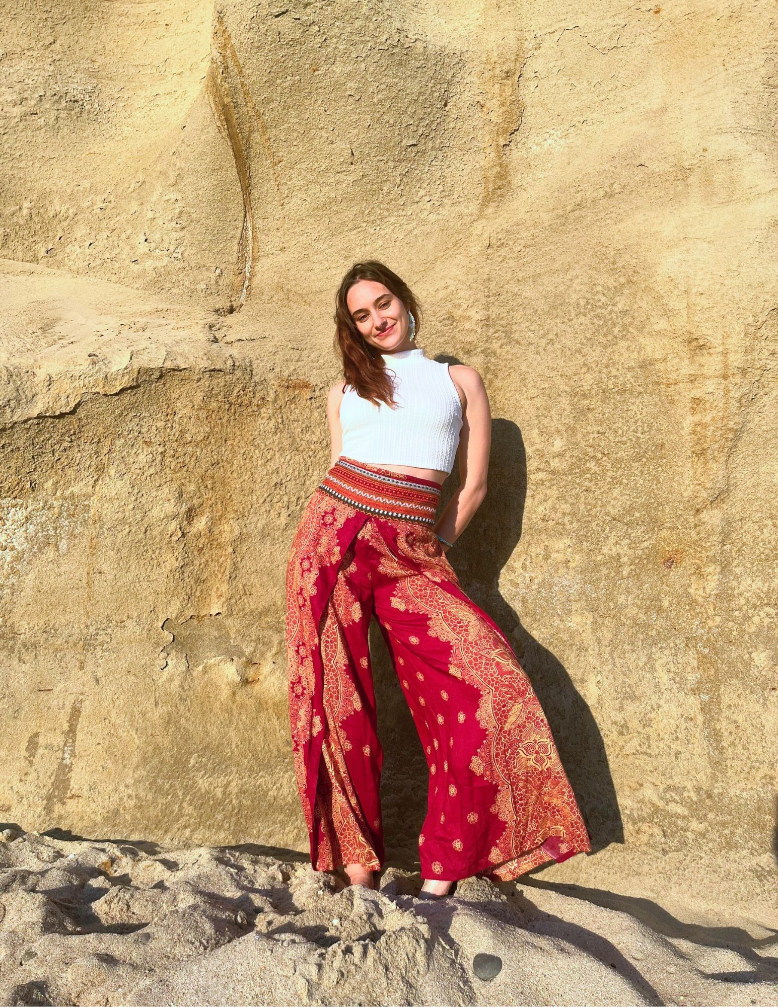 Vanessa Wasbin standing against a sandstone cliff in red patterned pants