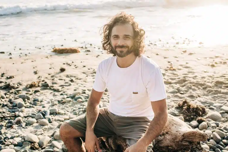 Christian Gentile smiling on a rocky beach at sunset