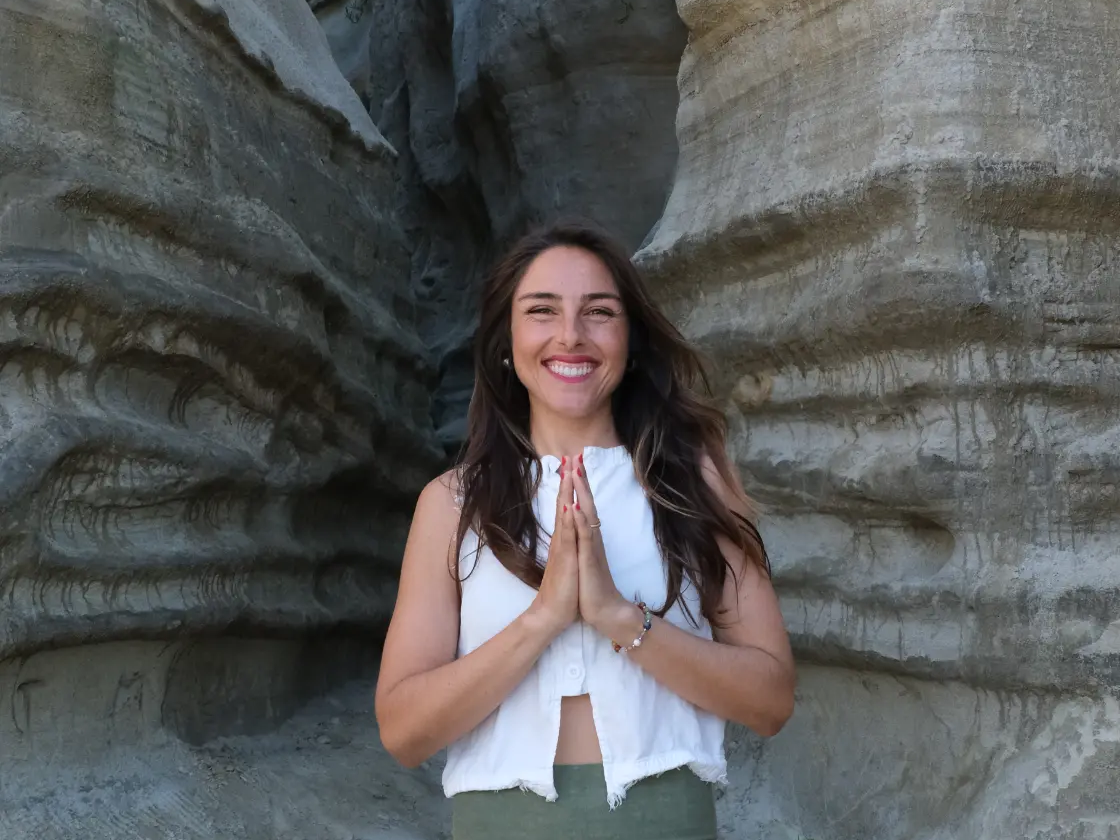 Julia Solazzo in a yoga prayer pose between coastal rock formations
